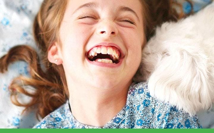 Girl laughing while a puppy snuggles up to her